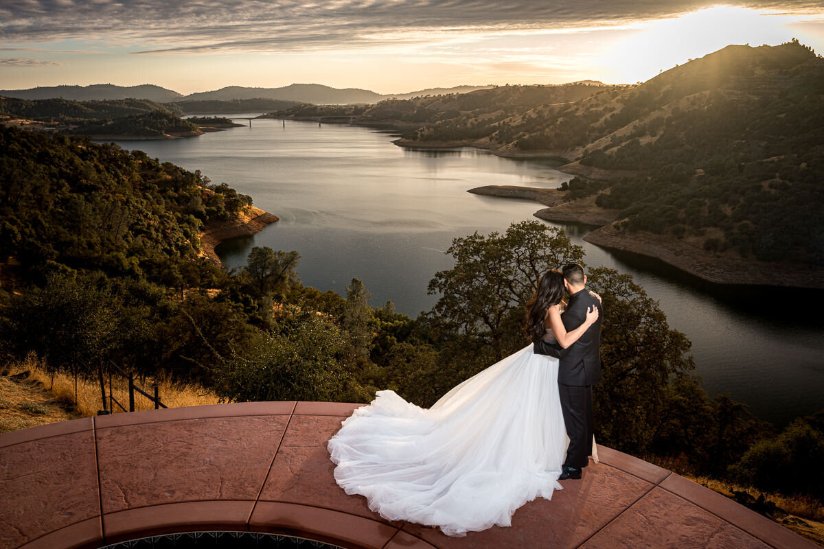 A romantic moment as the bride and groom share a sunset kiss, framed by the rolling vineyards of Airola Road in Murphys, CA.