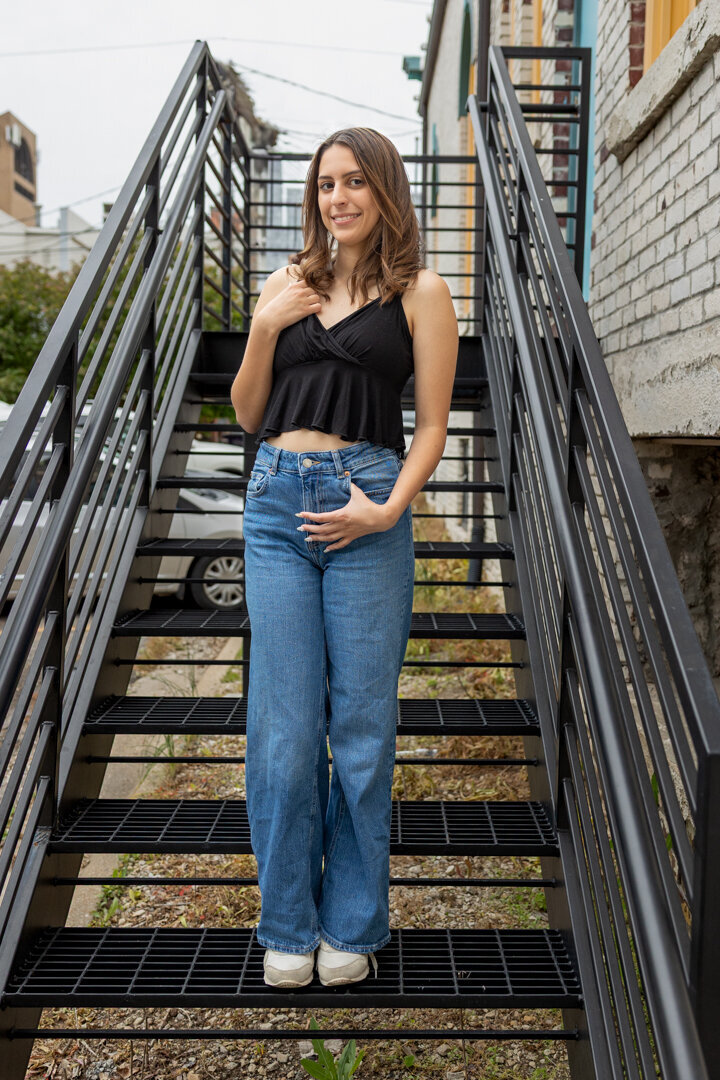 A senior girl standing on black metal stairs in downtown Lawrence, KS