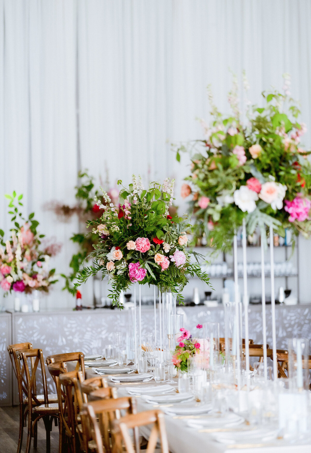 Elegant table settings with lush raised flower centrepieces at a wedding reception.