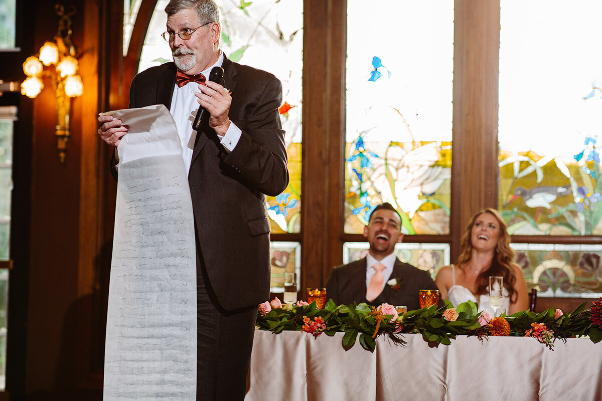 Father of the bride reads his long speech to the wedding couple at their reception.