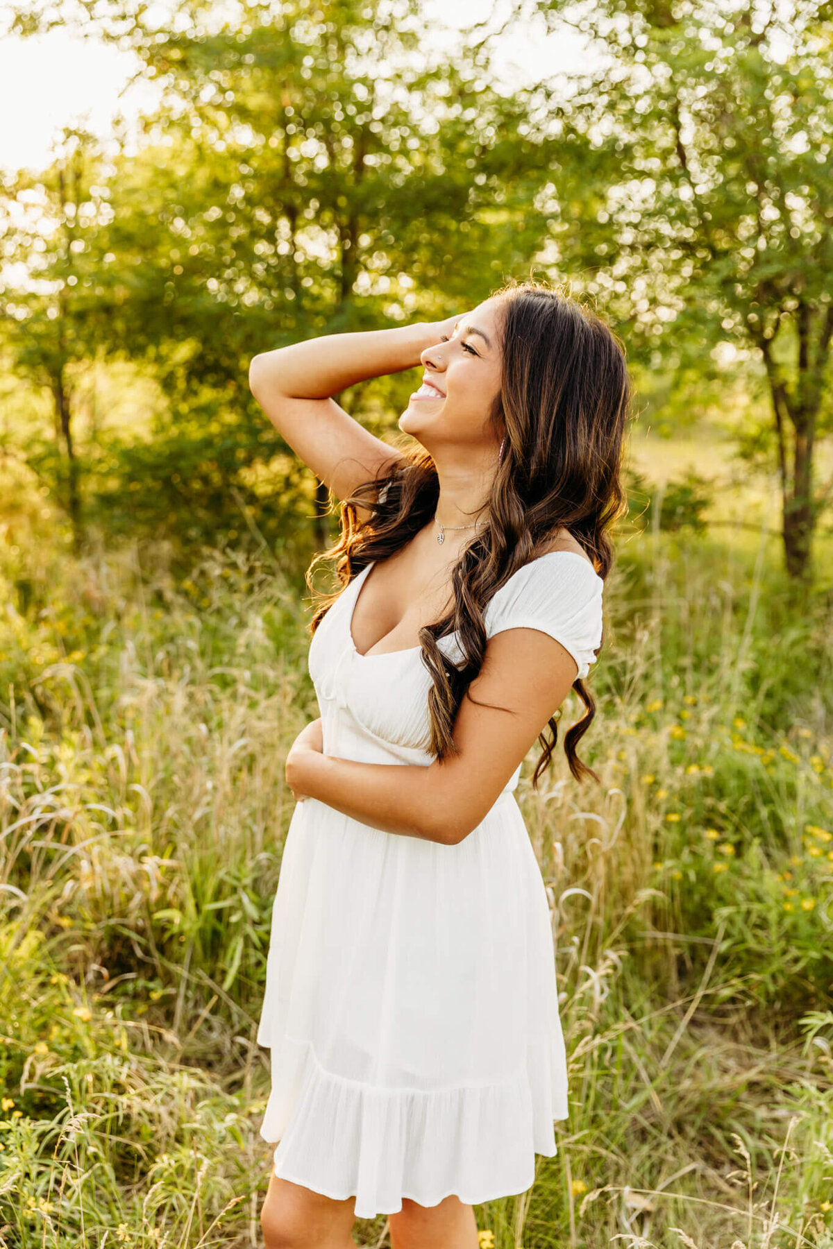 high school girl playing with her hair and glancing up towards the sky in a field near Oshkosh