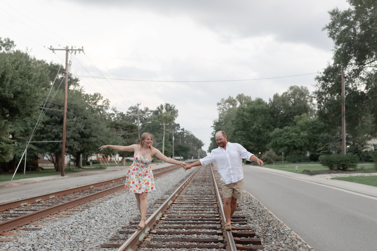 bride and groom holding hands on railroad track