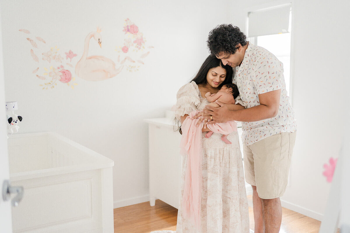 mum and dad holding newborn baby in their nursery taken by travelling newborn maternity photographer in Gold Coast.