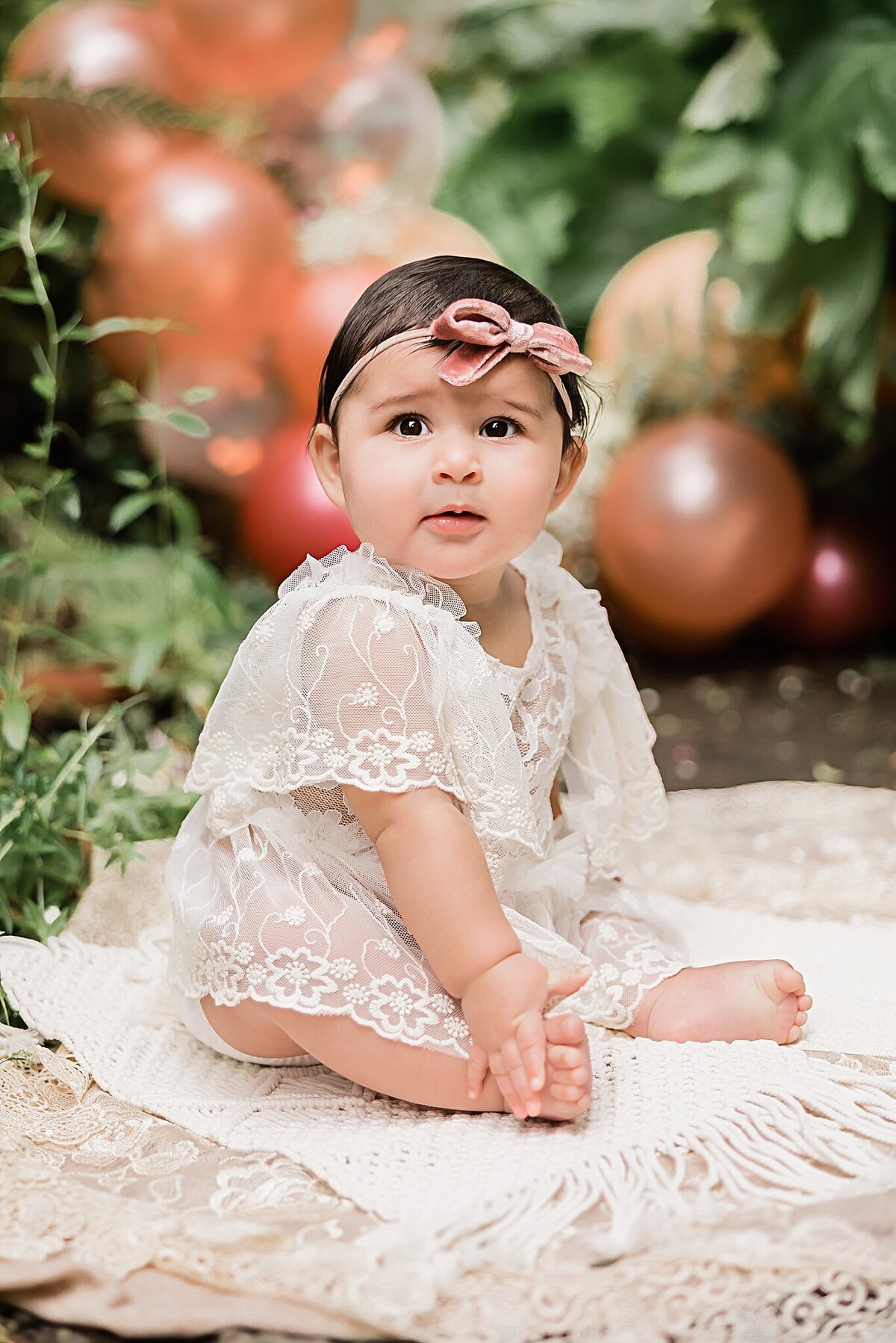 baby girl in lace dress in front of balloons in beaverton birthday baby session