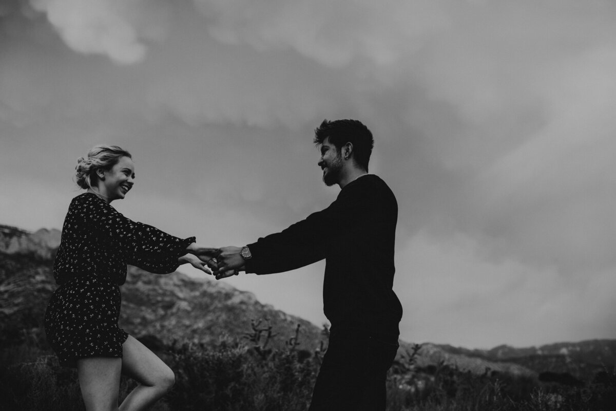 engaged couple holding hands spinning in the desert