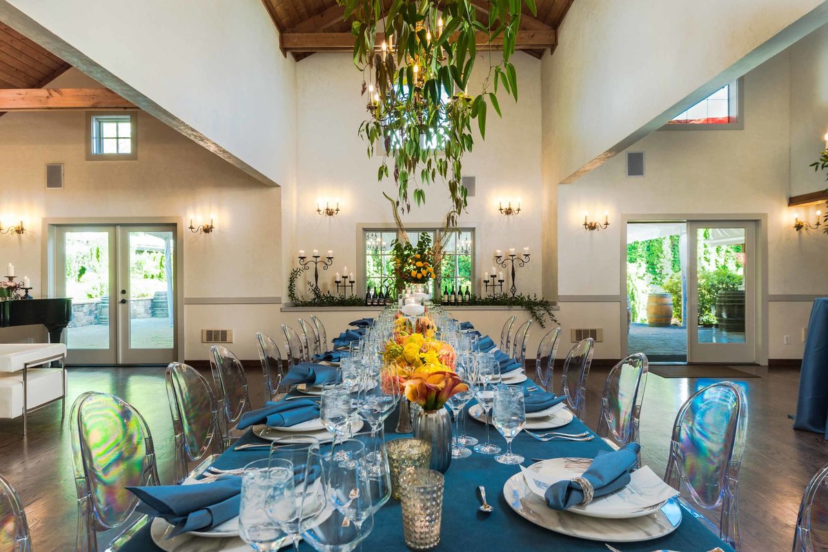 long dinner party table at Chateau Lill with orange flower centerpiece and greenery chandelier