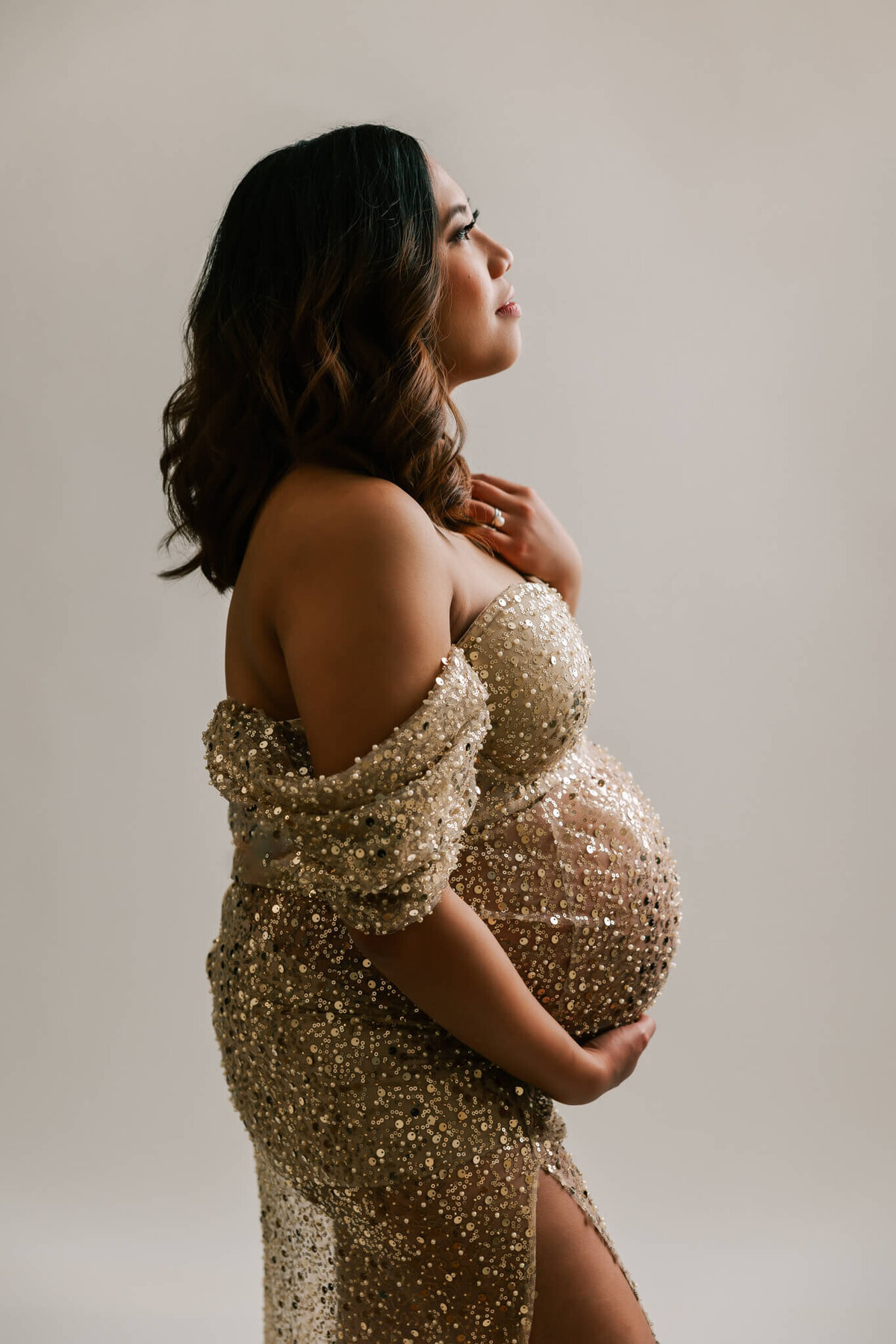 mom holding belly and neck wearing gold dress  in pdx maternity photography by ann marshall