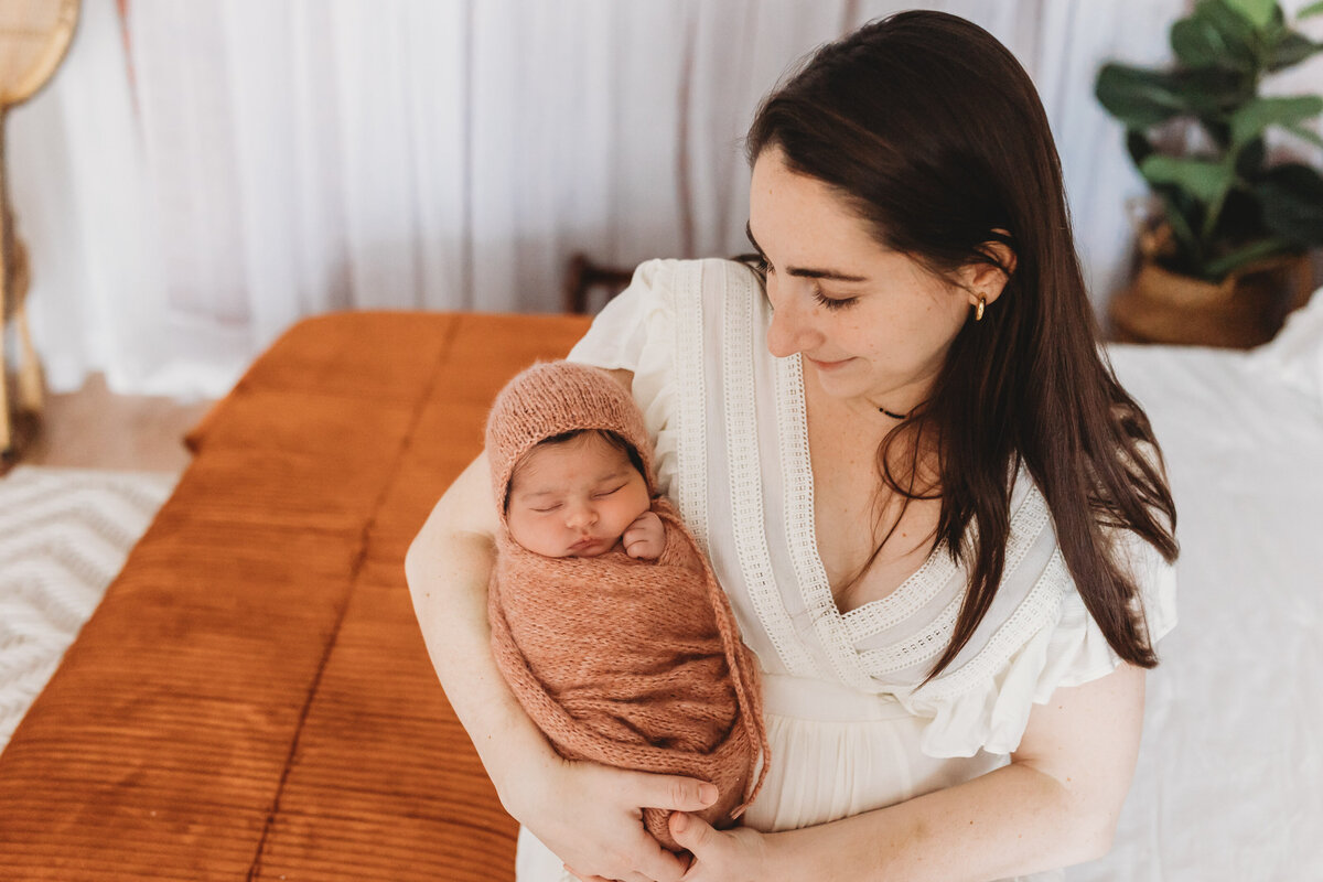 mom holding baby girl in bonnet in studio by harrisburg pa newborn photographer