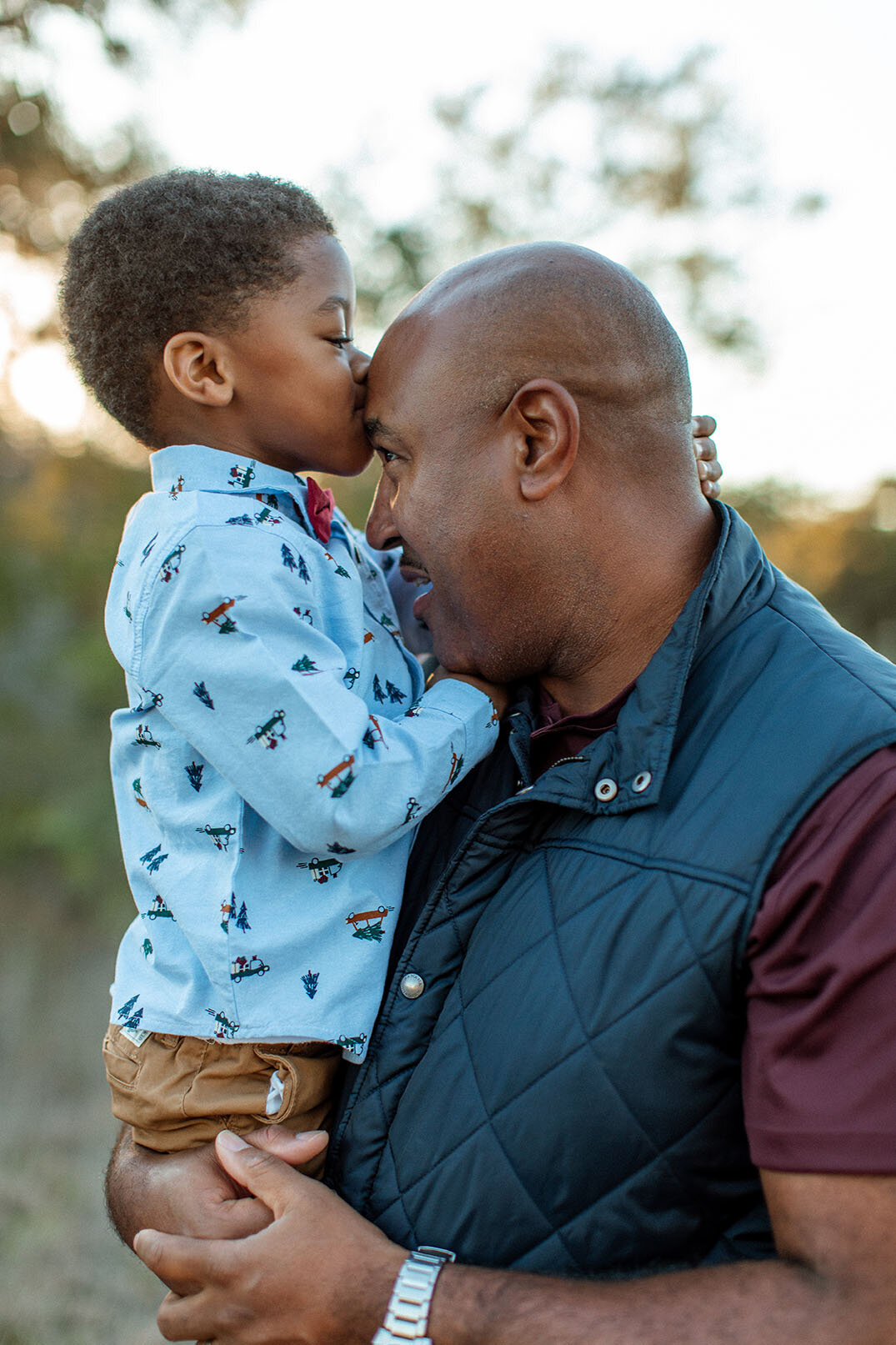 Candid outdoor portrait of a child kissing their dad on the forehead, captured by San Antonio photographer Sara James.