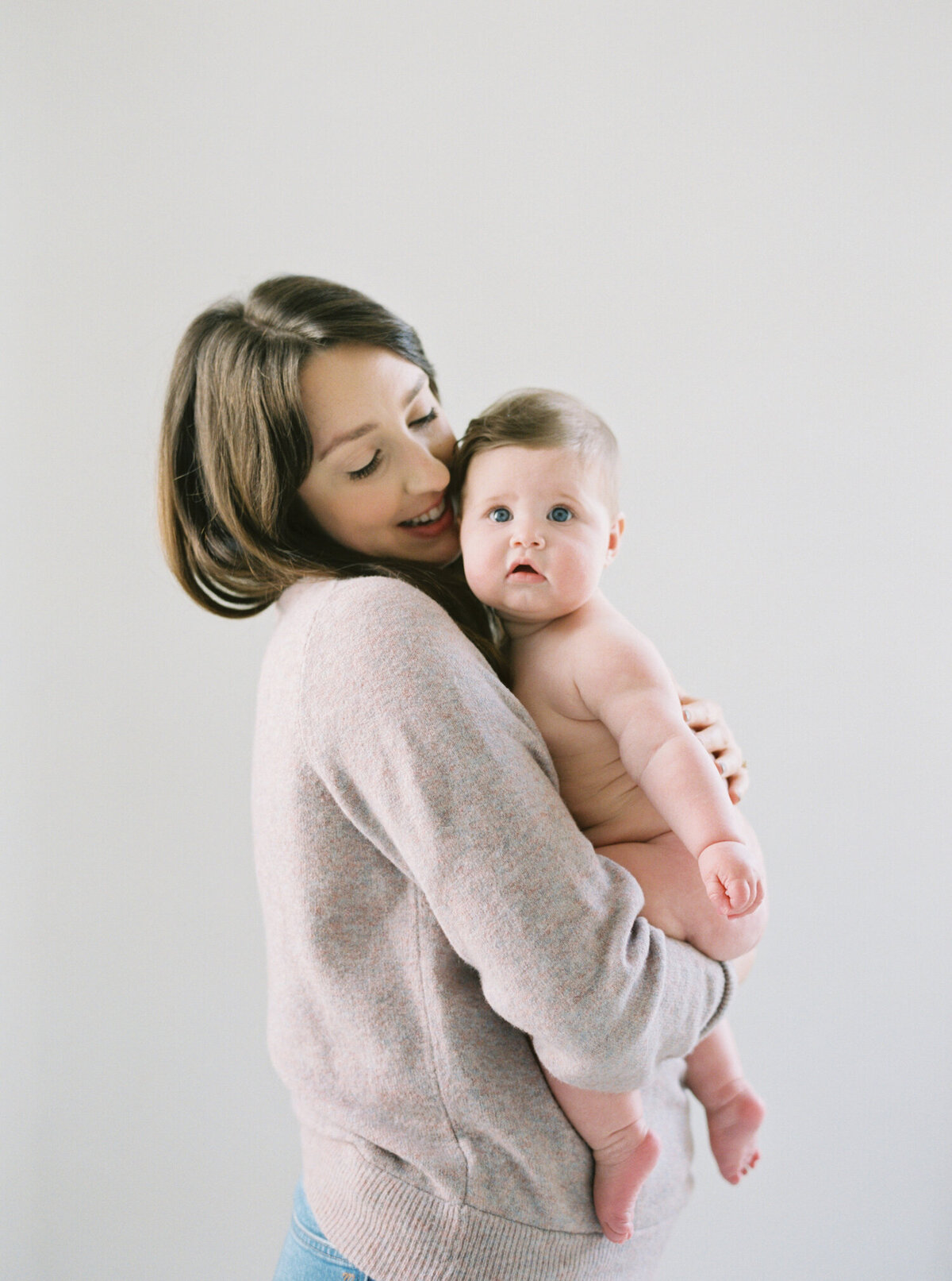 mom holding her squishy 6 month old baby naked in the studio shot on film