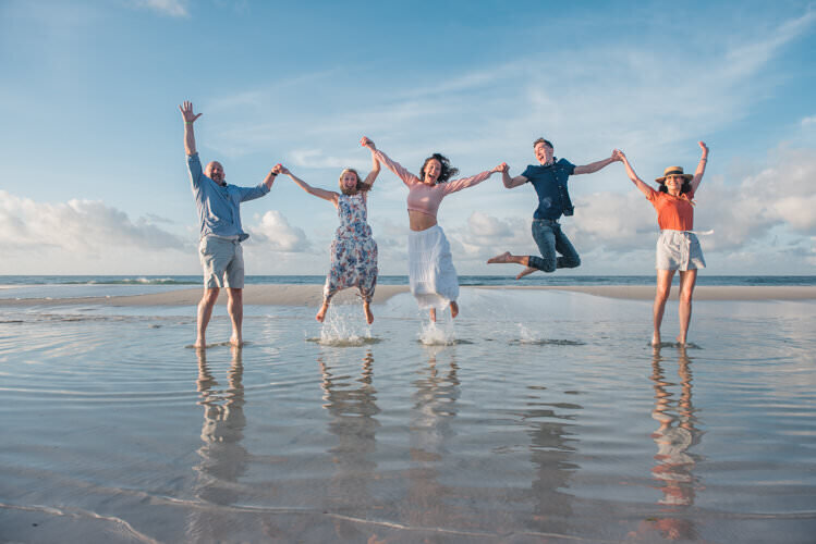 family jumping at water's edge at Pensacola Beach
