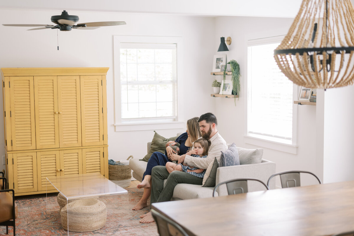 Portrait of a family in their living room holding their newborn baby in Charleston South Carolina