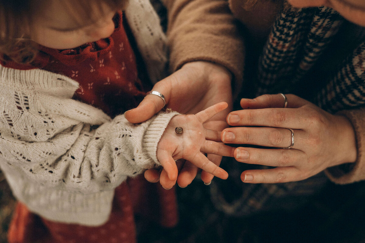 child holding up his hand with a bug inside to show his mom