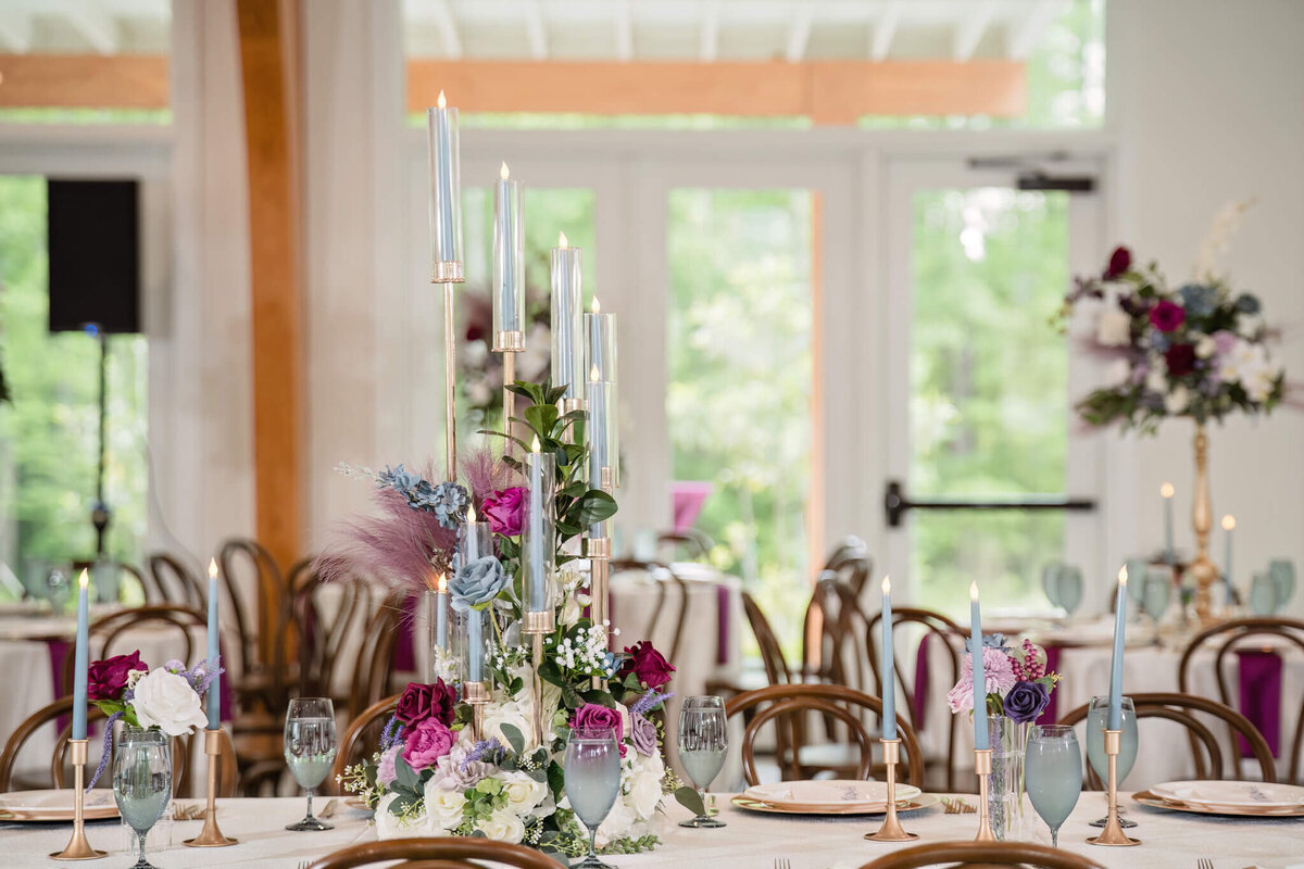 Chic wedding reception table featuring deep purple florals and gold details.