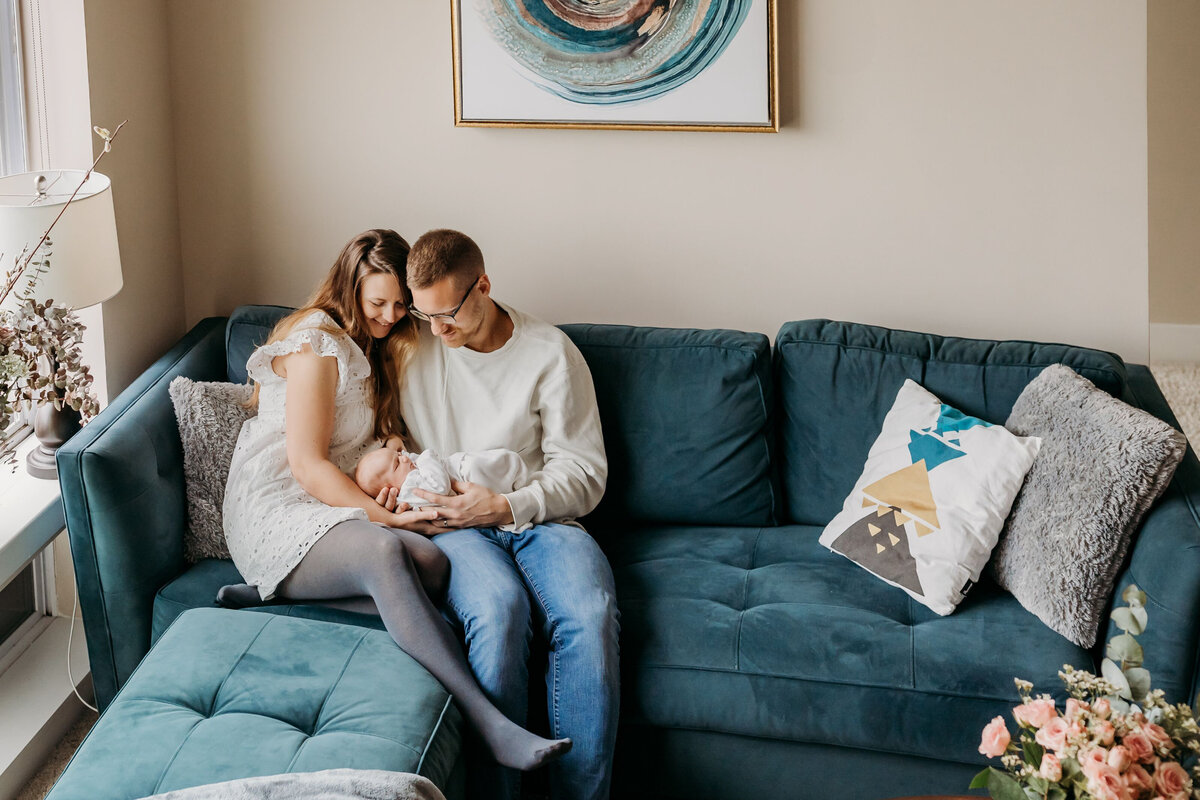 birds eye view of a couple sitting on a teal couch while holding their newborn