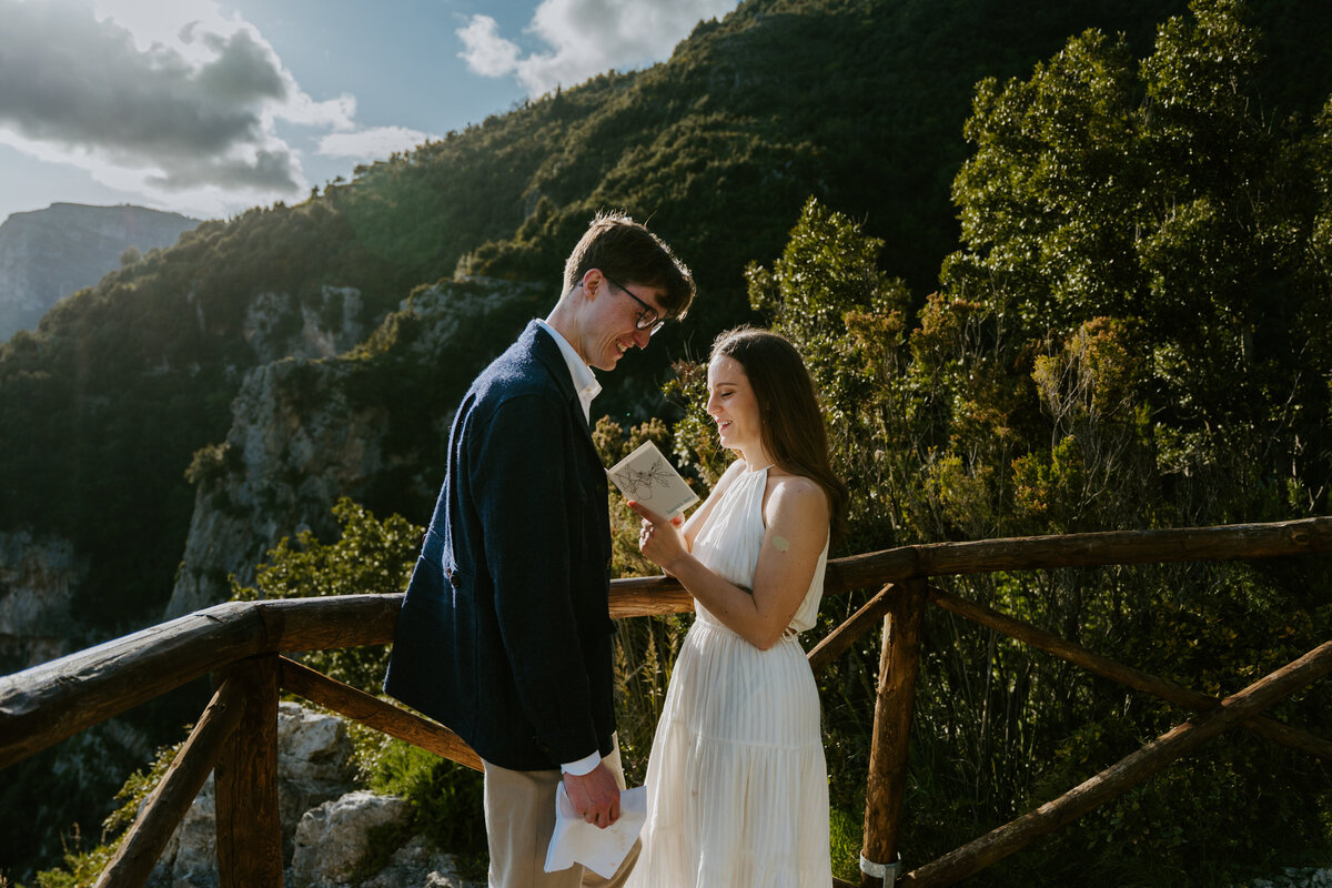 Couple reading vows at wooden railing.
