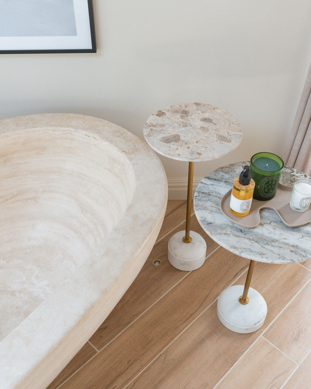 Aerial view of a large wooden bathtub and two small stone side tables with decor.