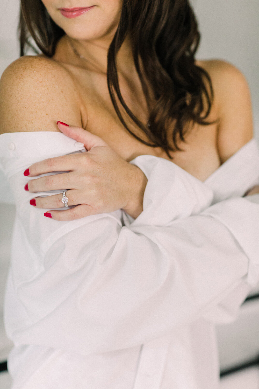 Woman wears partner's white shirt for boudoir shoot.
