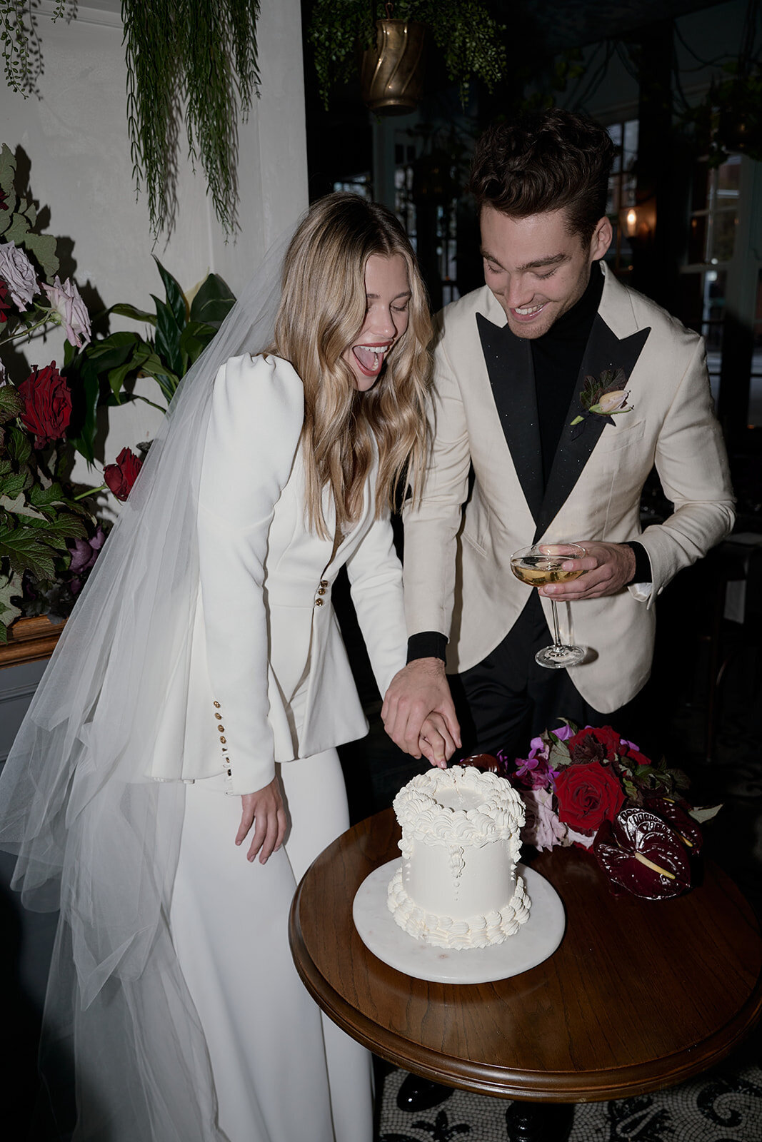 Bride and groom cutting the cake together while having fun and drinking champagne after their ceremony at Kittyhawk in Sydney.