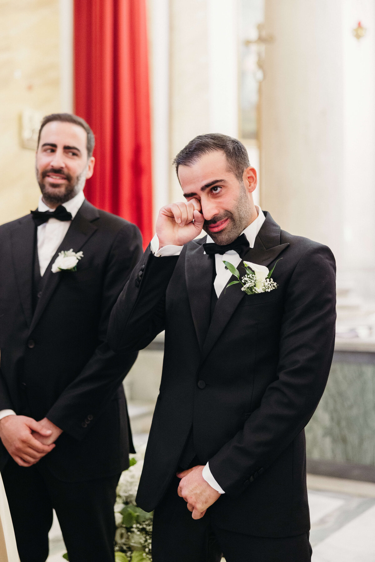 Groom smiling emotionally as he sees the bride walking down the aisle

