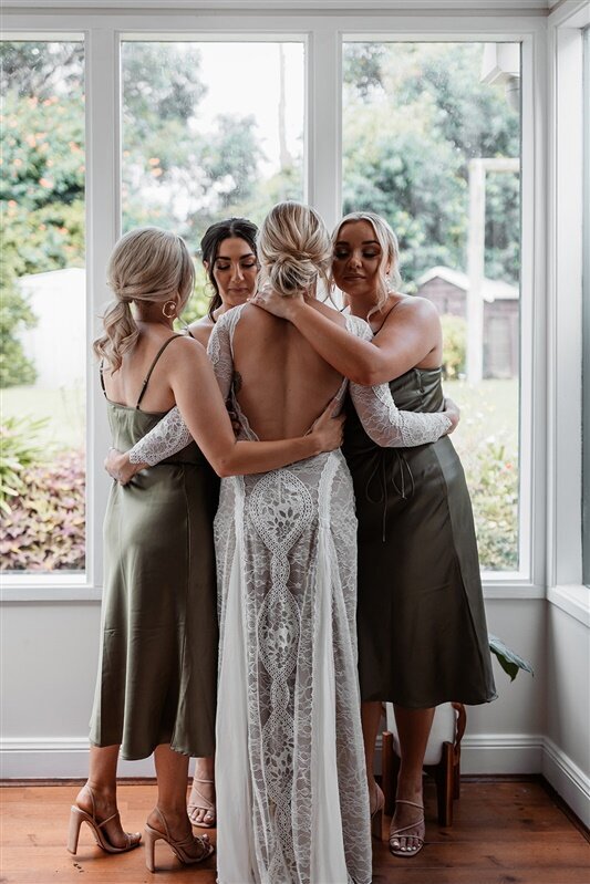 "Capture the heartwarming moment of bridesmaids embracing the bride in a joyous first look! Our professional photographers specialize in candid shots that showcase the genuine emotions shared between the bride and her closest friends.