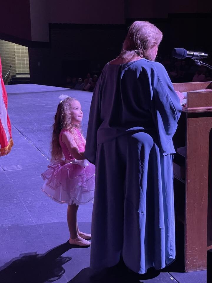 one of the little girls helping miss patti give her speech at recital