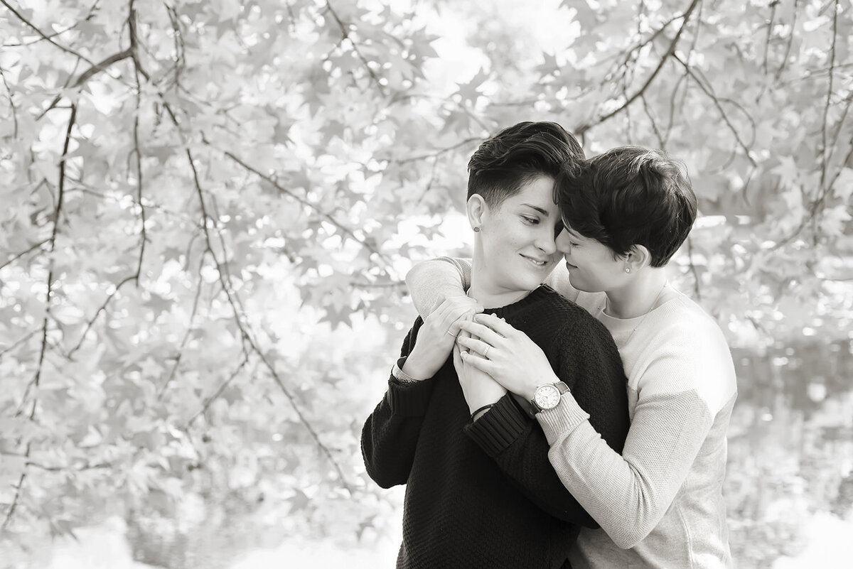 A person hugging their partner behind as they lean in for a kiss