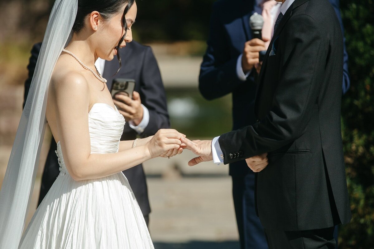 Bride putting ring on grooms finger