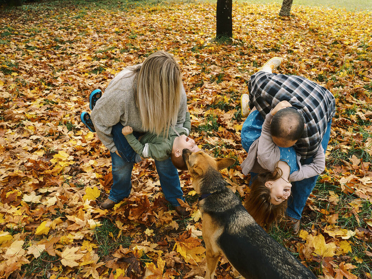 A family plays outdoors in the fall with leaves