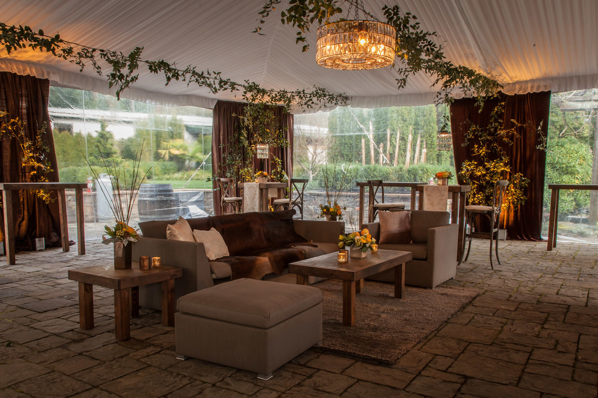 corporate party at Chateau Lill tent with ceiling greenery, lounge furniture, and yellow flowers, and brown draping