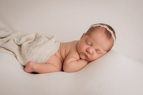 Baby girl sleeping for newborn portrait session with Atlanta Georgia newborn photographer snuggled up on her side on neutral fabric backdrop