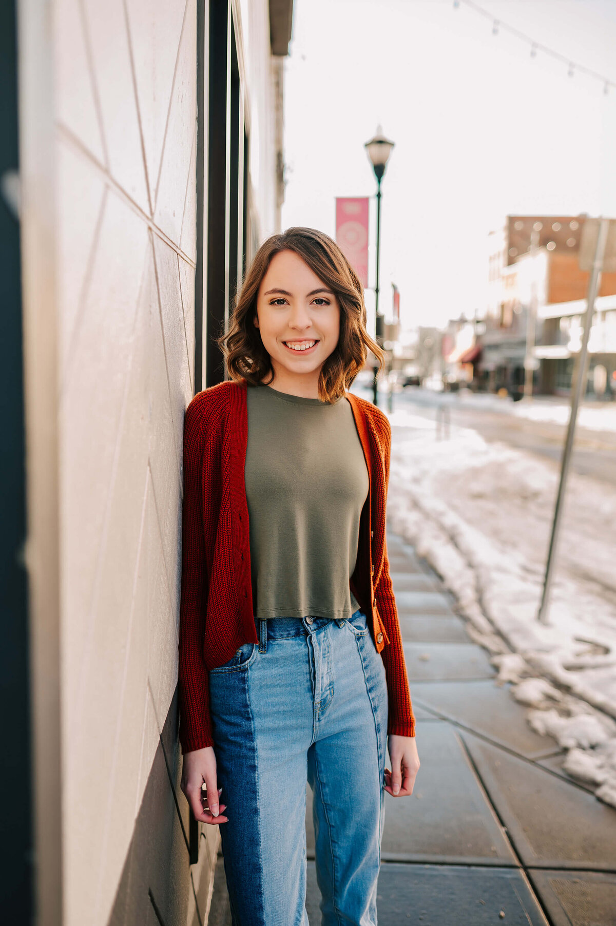 girl leaning against brick wall downtown Branson during senior photography session