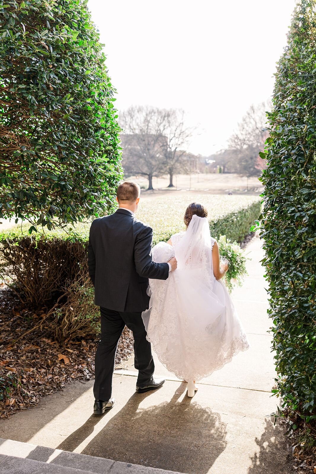 Bride and groom walk down tree lined path