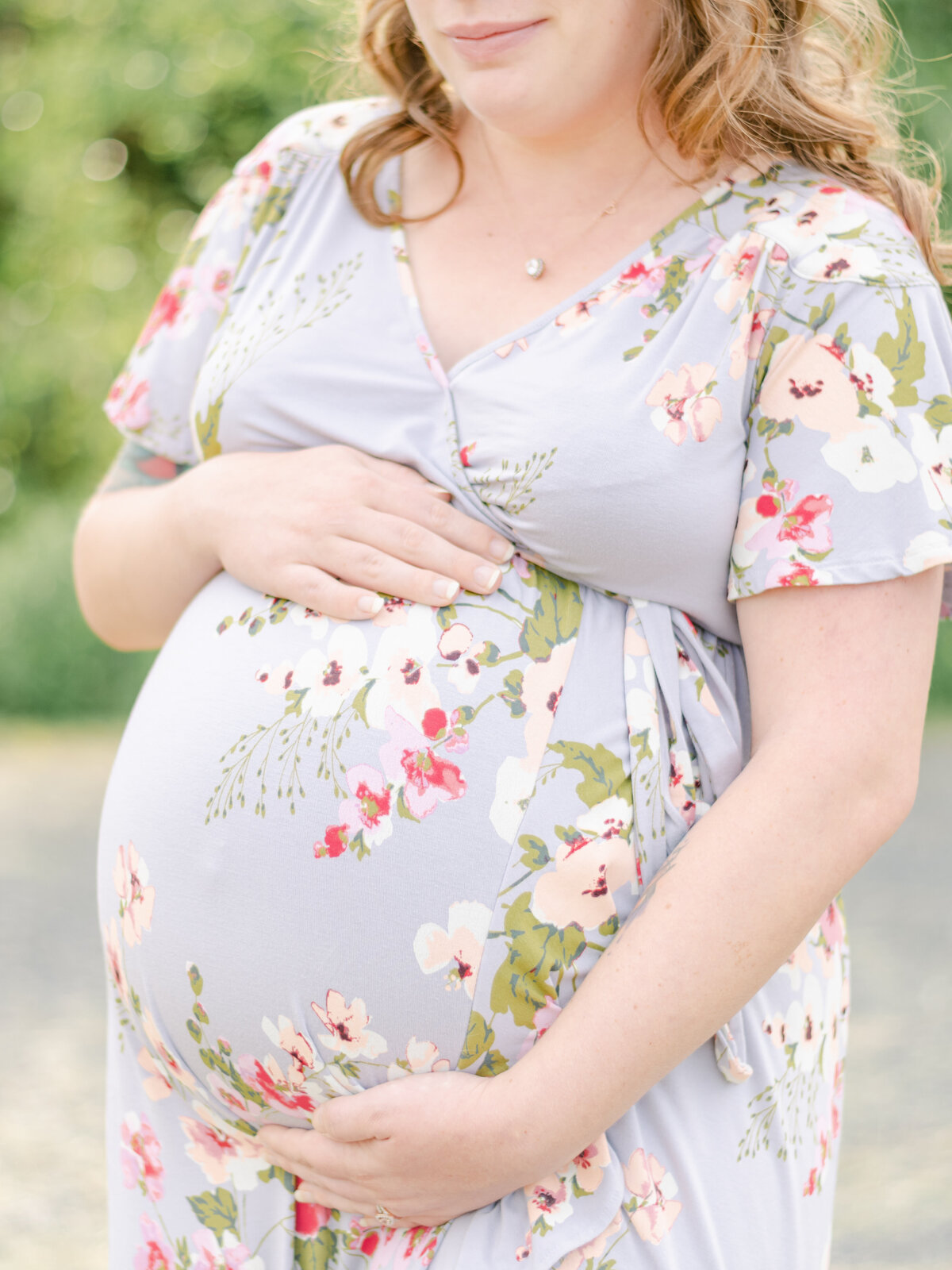 Close up photograph of a moms pregnant belly in a floral dress.