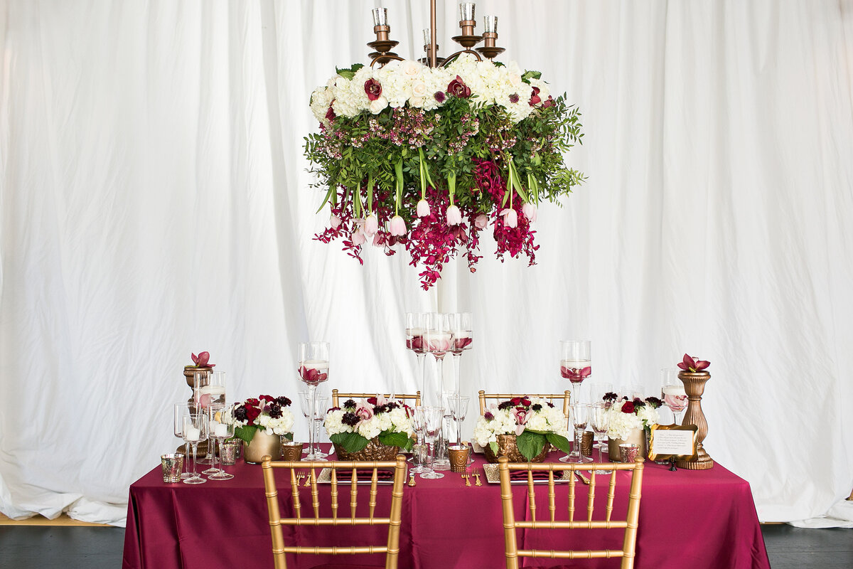 Burgundy sweetheart table with floral chandelier