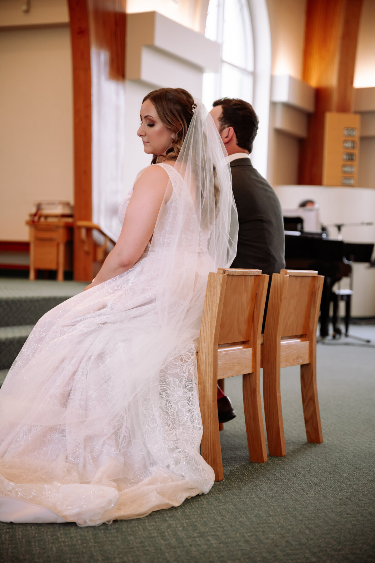 bride and groom sitting in chairs at the top of alter on wedding day
