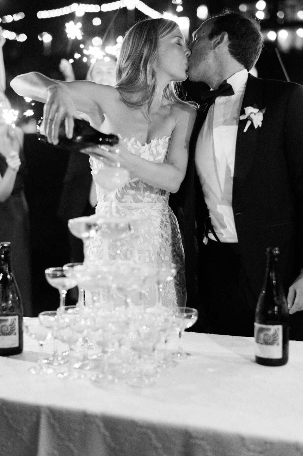 Bride pours champagne over a tower of glasses