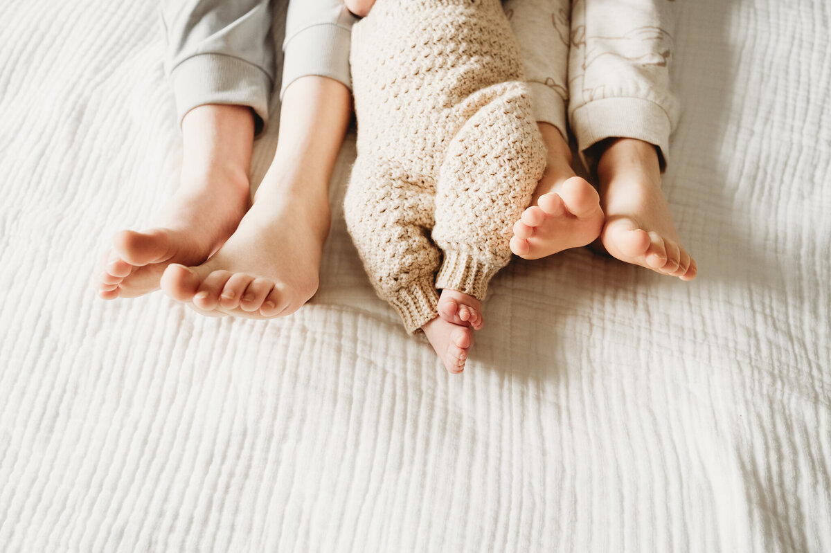 A newborn baby boy hangs out with his big brothers during a newborn session in their Mandan, ND home that captures just how tiny his toes are compared to big brothers.