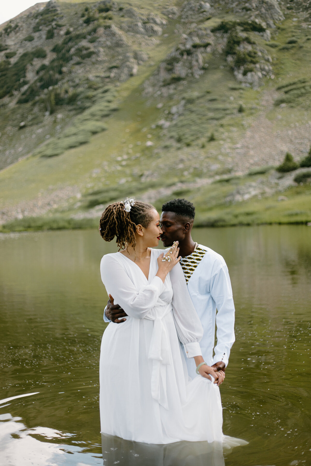 A bride and groom embrace while standing in a lake at Loveland Pass, Colorado.