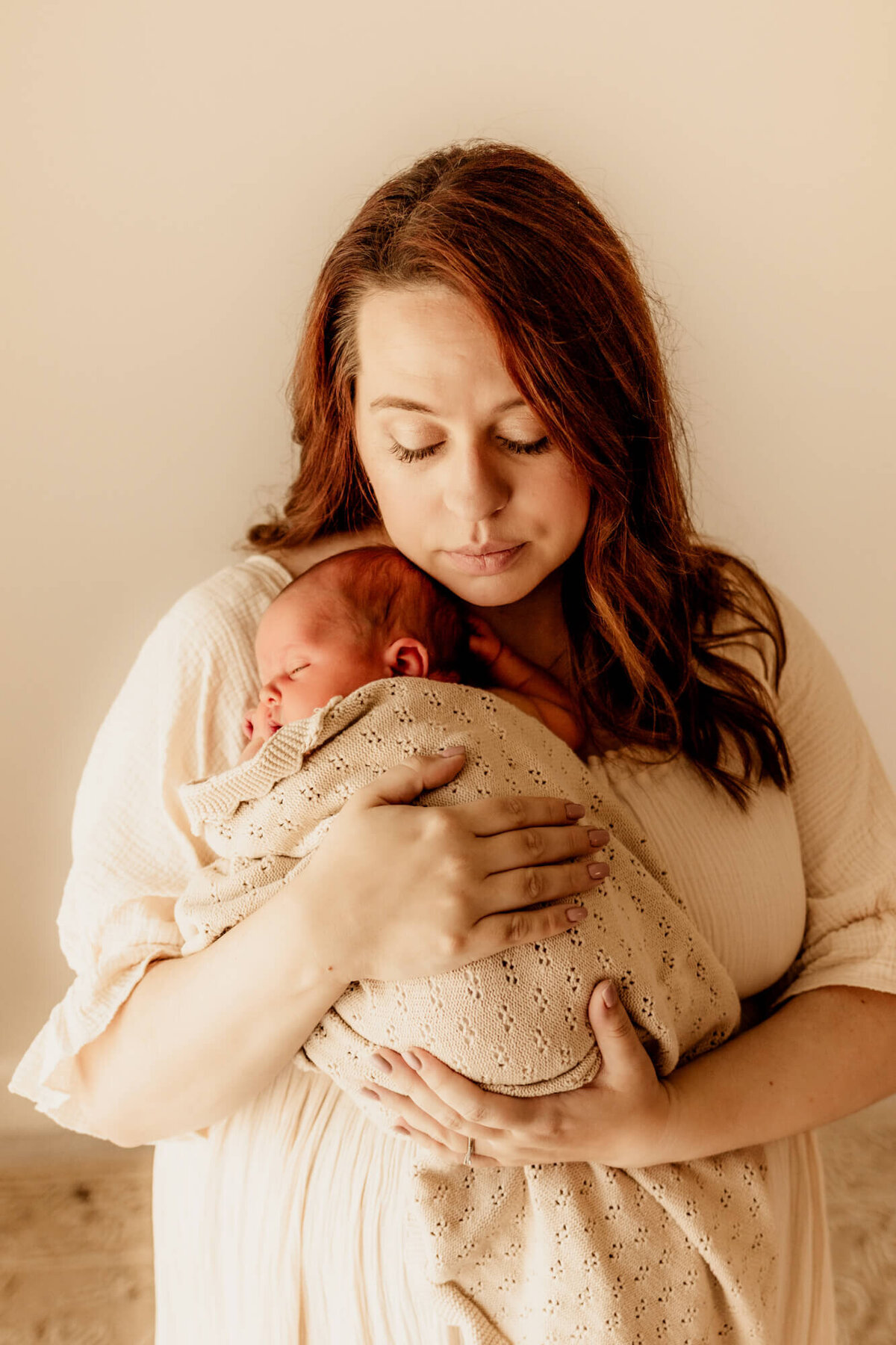 Mother looks down with her chin near her baby while he sleeps as she closes her eyes, Yukon Oklahoma.