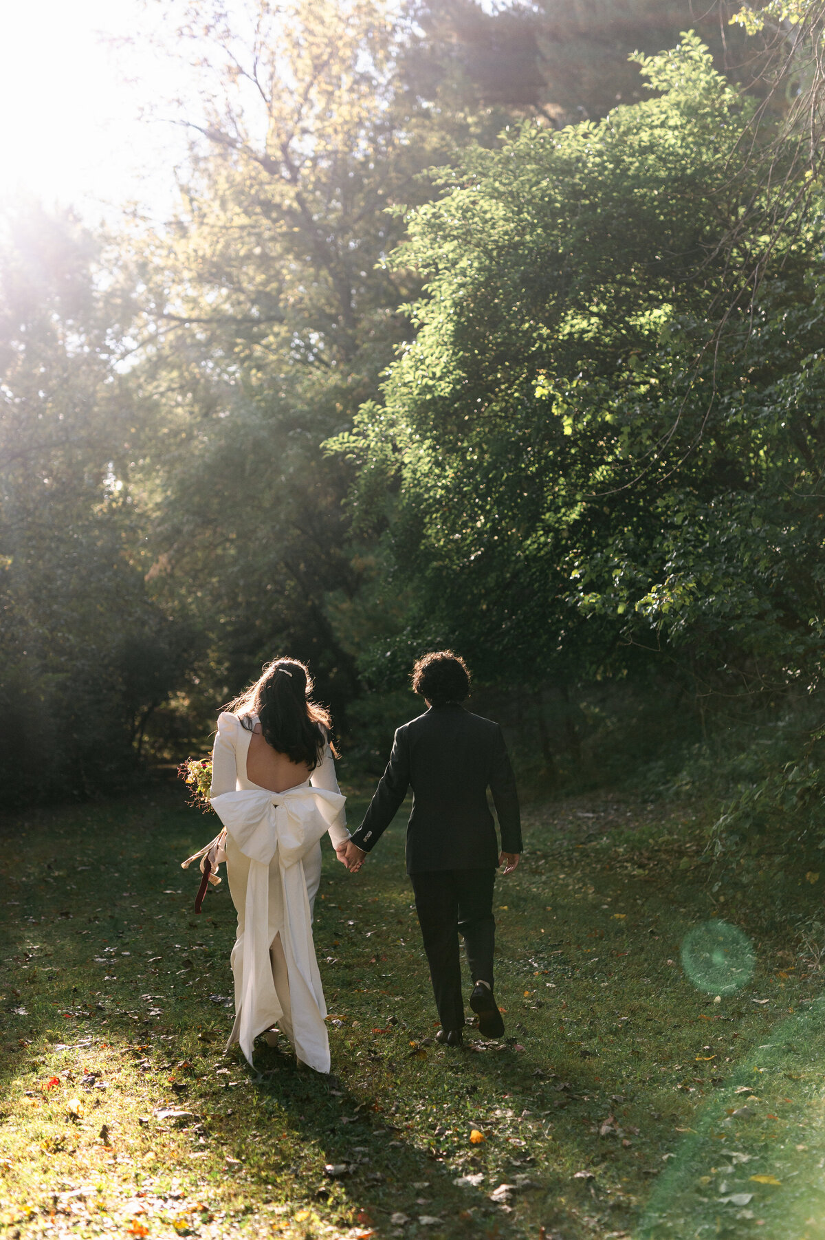 Bride and groom holding hands walking away from camera