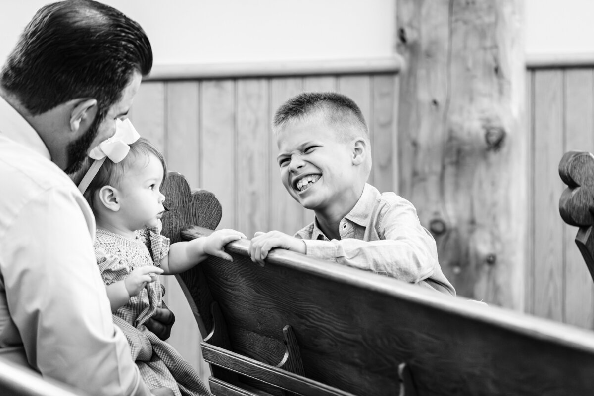 Child laughing in church pews during wedding at Big Sky Chapel in Big Sky, MT