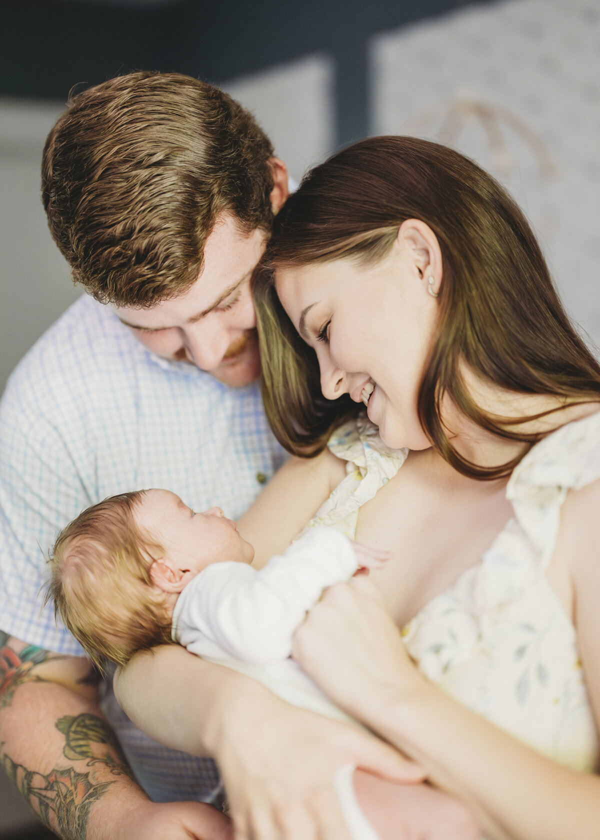 Parents cuddling their newborn and toddler during a cozy Kansas City family photography session at home.