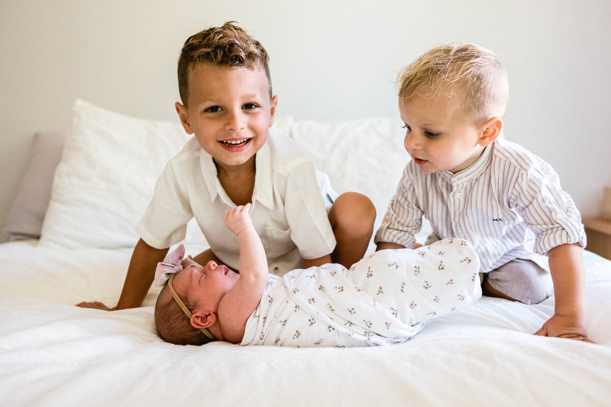 Two brothers looking at their newborn baby sister