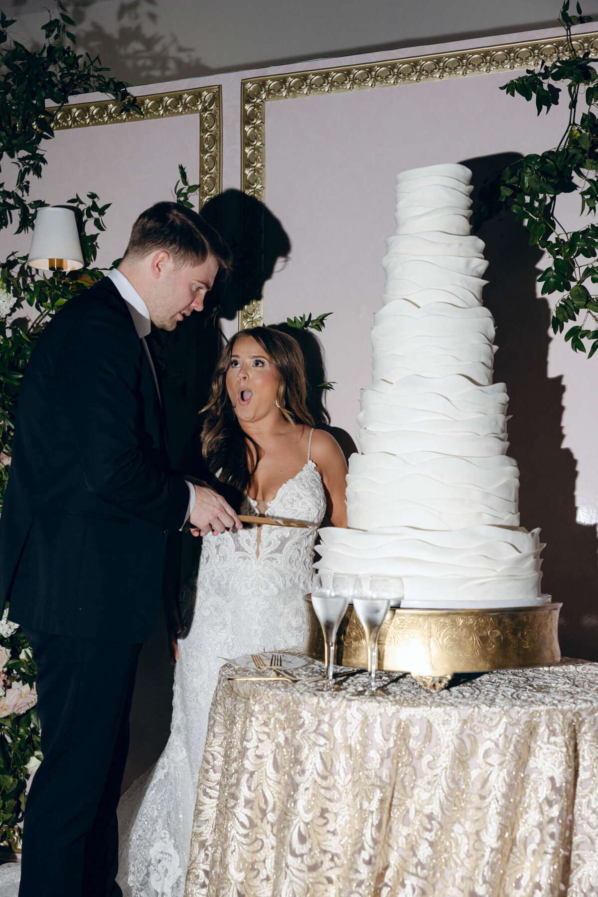 A wedding photo of the bride and groom cutting their white wedding cake