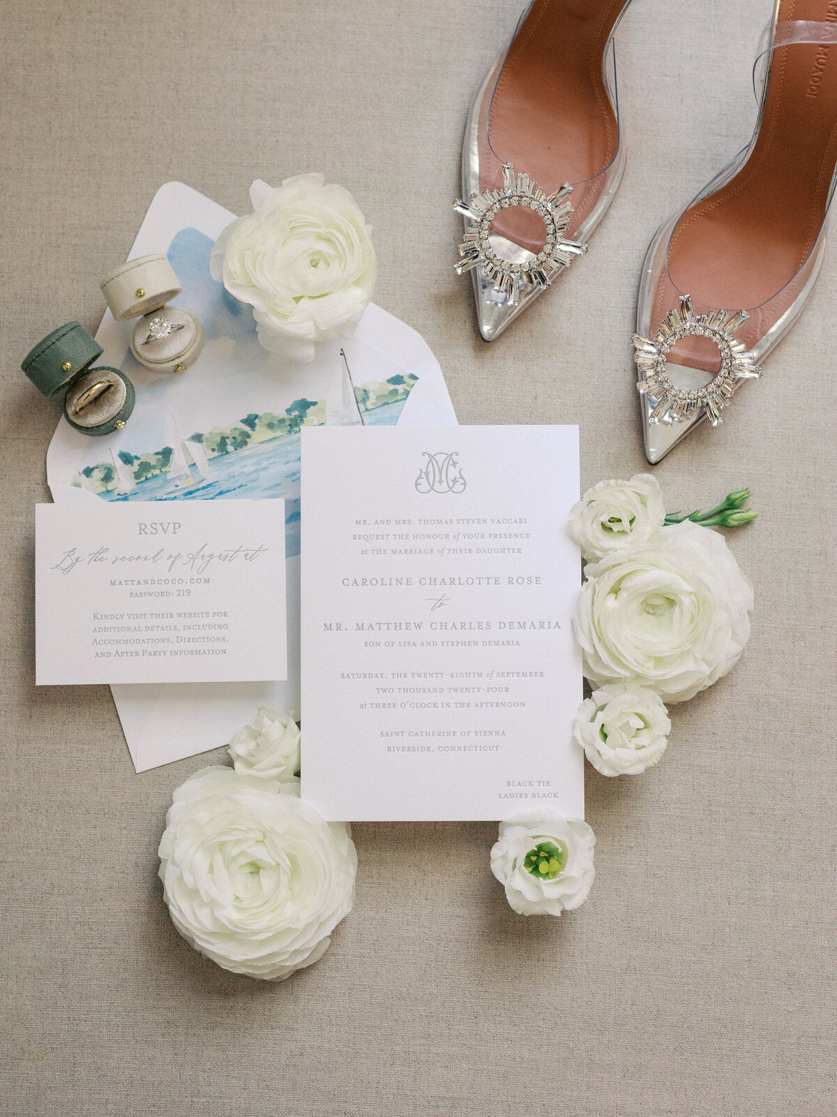 wedding day details with invitations and rings on a linen backdrop