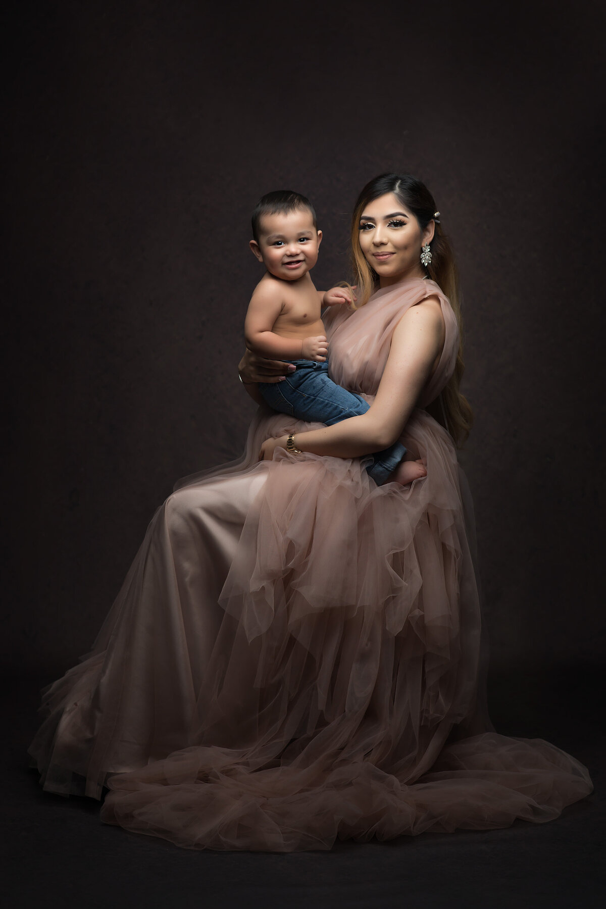 A mother lovingly holds her smiling son in a studio session with a Dallas family portrait photographer.