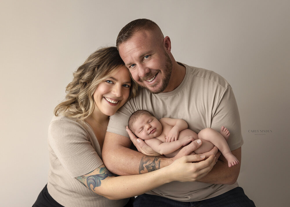 NEWBORN_BABYGIRLSMILINGWITHPARENTSBEIGE