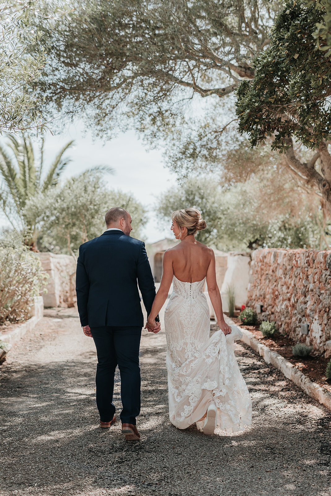 Bride and Groom walking hand in hand along cobble pathway at their wedding in Sant Lluis Menorca