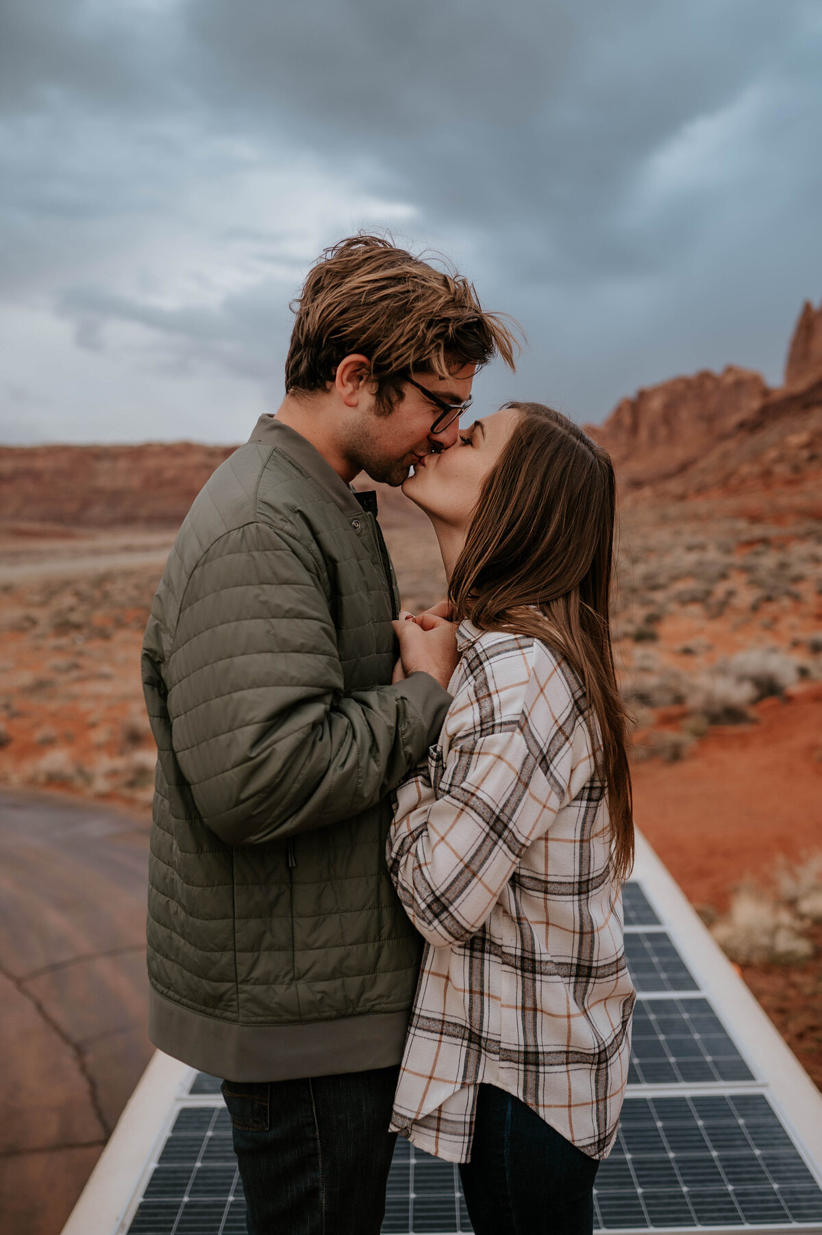 engaged couple posing on camper van in the desert 